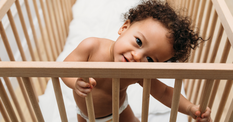 Logo for A toddler standing up in a crib